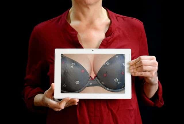 die Frau hält ein Foto ihrer Oberweite in einem Push-up-BH